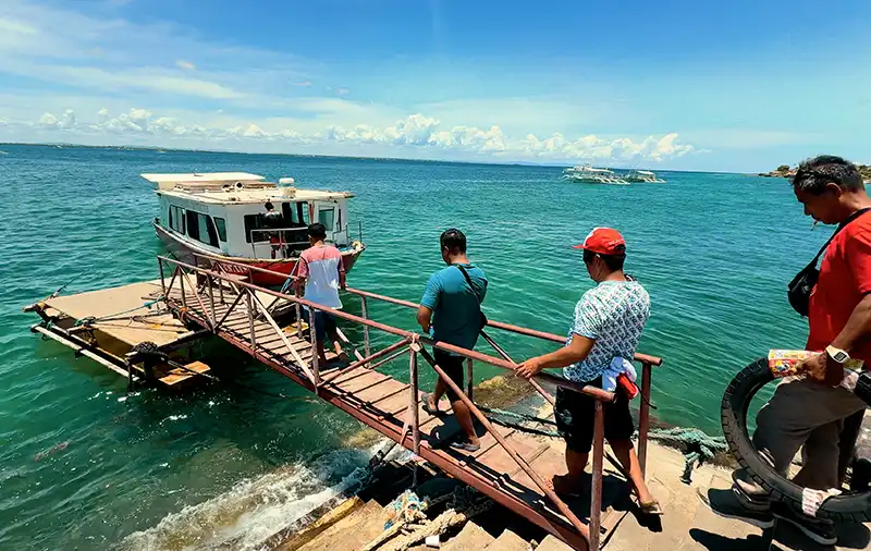 Passengers boarding a small boat via a ramp at Angasil Port in Mactan, heading to Olango Island, Cebu