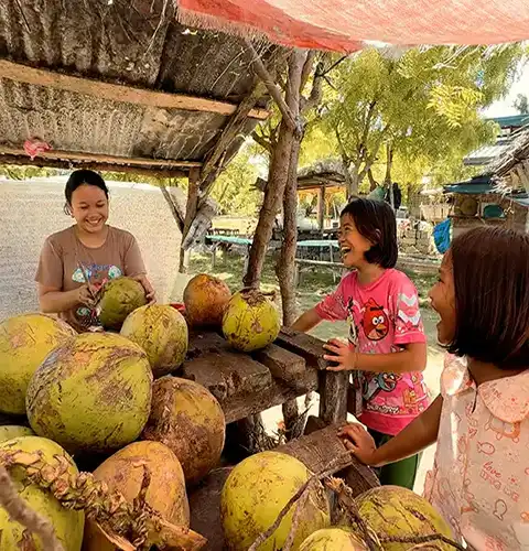 Fresh coconut stand with smiling vendor on Olango Island