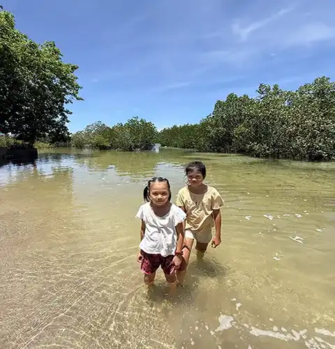 Two kids standing in the shallow waters near a mangrove forest on Olango Island